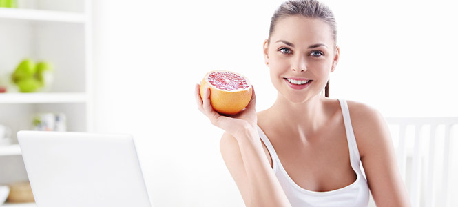 img of woman with healthy skin and good nutrition holding up a fruit